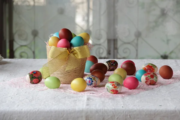 Velikonoční vajíčka v košíku a na stole — Stock fotografie