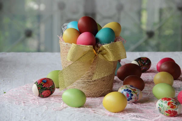 Ovos de Páscoa na cesta e na mesa — Fotografia de Stock