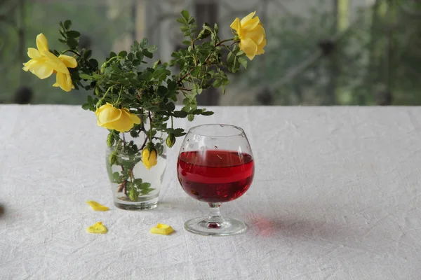 Vino tinto en la copa y un ramo de rosas amarillas — Foto de Stock