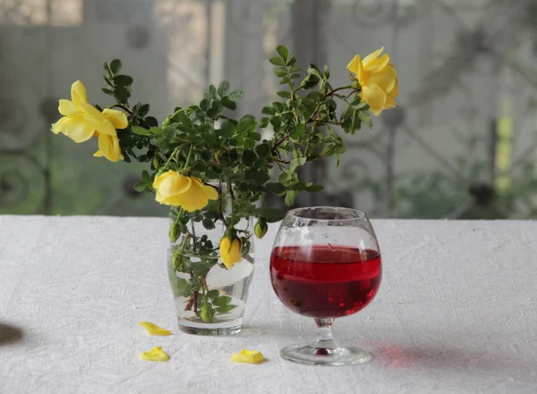 Vino tinto en una copa transparente y un ramo de rosas — Foto de Stock
