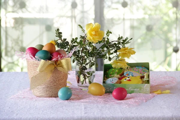 Biscuits de Pâques dans une boîte et œufs de Pâques dans un panier — Photo