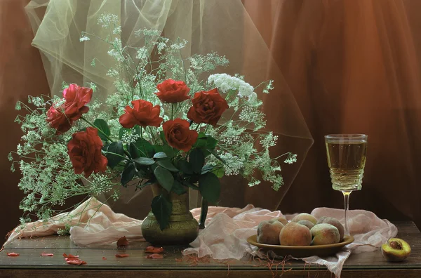 Witte wijn in een glas, perziken en een boeket rozen — Stockfoto