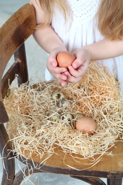 Egg in the hands of a child, the quail eggs in a simulated nest — Stock Photo, Image