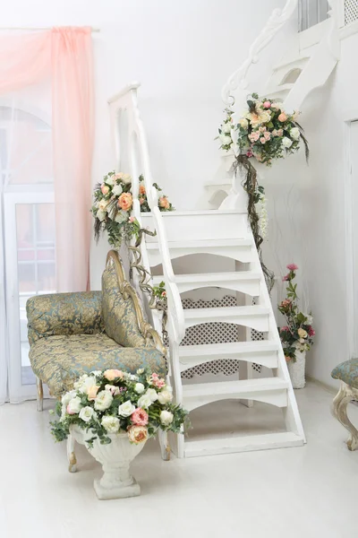 Belles fleurs dans des vases sur des escaliers blancs et un canapé — Photo