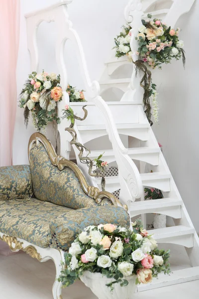 Hermosas flores en jarrones en escaleras blancas y sofá —  Fotos de Stock