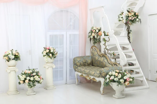 Schöne Blumen in Vasen auf weißen Treppen und Sofa — Stockfoto