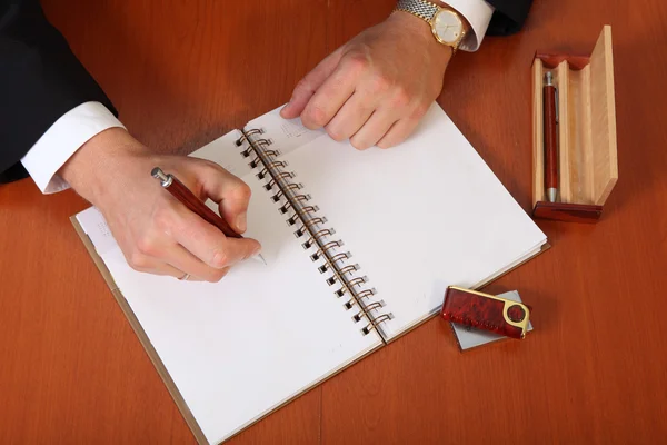 Männerhände halten Stift und Block auf dem Tisch lizenzfreie Stockbilder