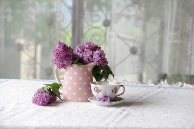 bir fincan çay ve bir buket masadaki leylak