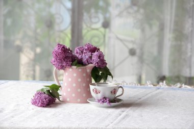 bir fincan çay ve bir buket masadaki leylak