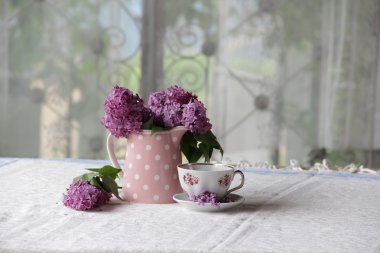 bir fincan çay ve bir buket masadaki leylak