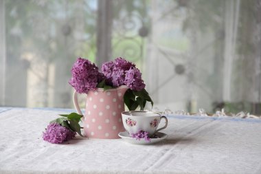 bir fincan çay ve bir buket masadaki leylak