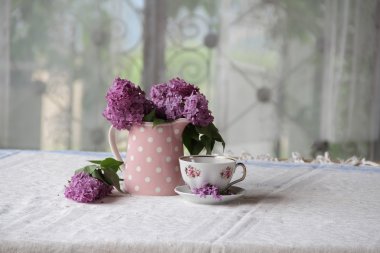 bir fincan çay ve bir buket masadaki leylak