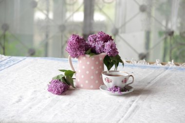 bir fincan çay ve bir buket masadaki leylak