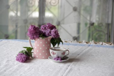 bir fincan çay ve bir buket masadaki leylak