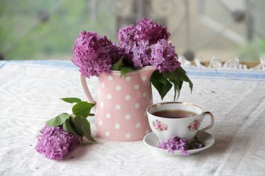 bir fincan çay ve bir buket masadaki leylak