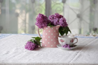 bir fincan çay ve bir buket masadaki leylak