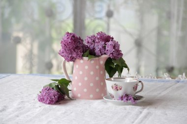 bir fincan çay ve bir buket masadaki leylak