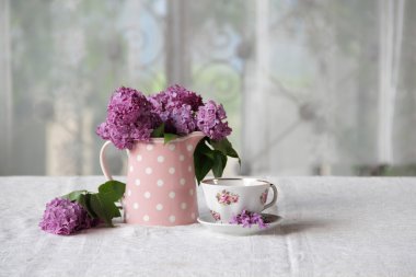 bir fincan çay ve bir buket masadaki leylak