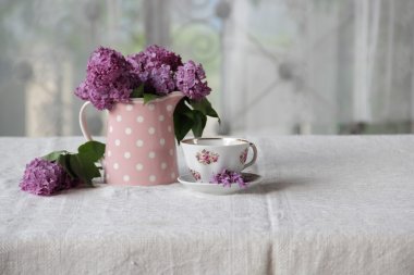 bir fincan çay ve bir buket masadaki leylak