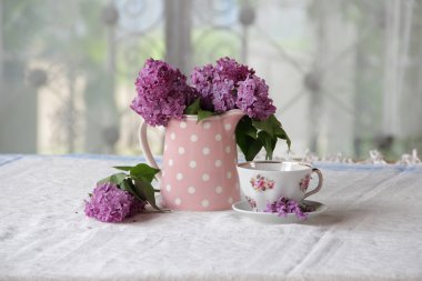 bir fincan çay ve bir buket masadaki leylak