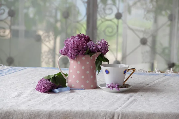 Strauß Flieder und Teetasse auf dem Tisch — Stockfoto