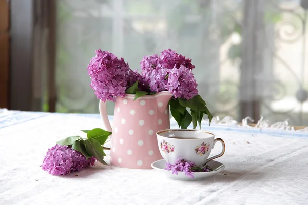 ライラックとテーブルの上の紅茶カップの花束 — ストック写真