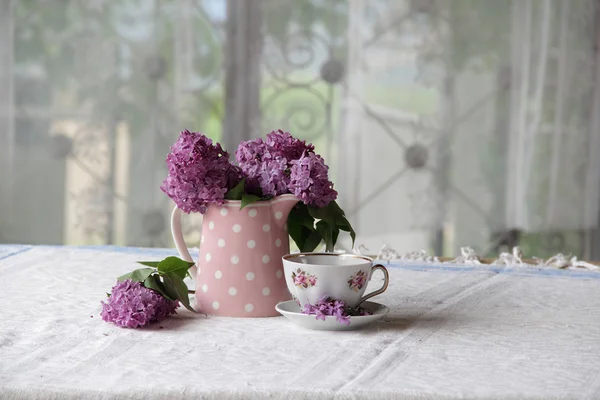 Na filiżankę herbaty i bukiet bzu na stole — Zdjęcie stockowe