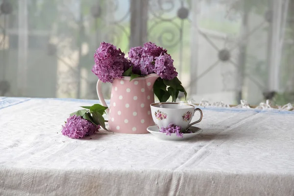 Une tasse de thé et un bouquet de lilas sur la table — Photo