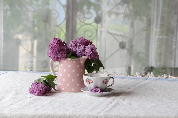 Uma xícara de chá e um buquê de lilases na mesa — Fotografia de Stock