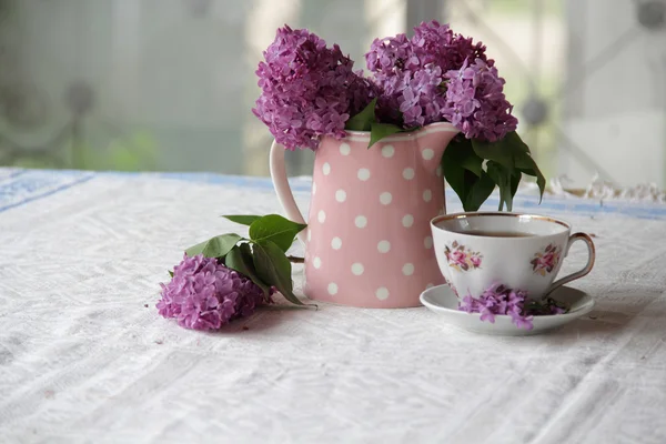 Secangkir teh dan karangan bunga lilac di atas meja — Stok Foto