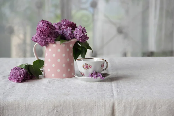 bir fincan çay ve bir buket masadaki leylak