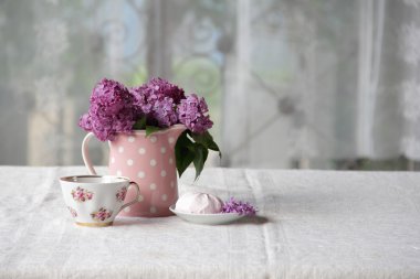 bir fincan çay ve şekerleme ve leylak sekmesinde bir buket