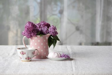 bir fincan çay ve şekerleme ve leylak sekmesinde bir buket