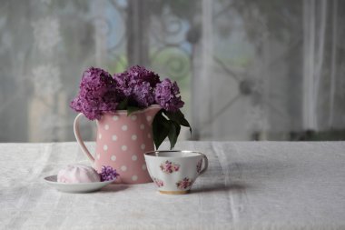 bir fincan çay ve şekerleme ve leylak sekmesinde bir buket