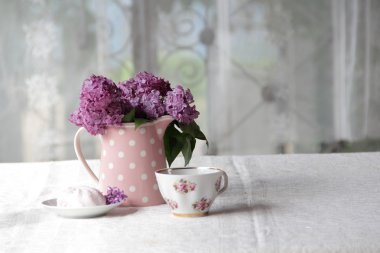 bir fincan çay ve şekerleme ve leylak sekmesinde bir buket