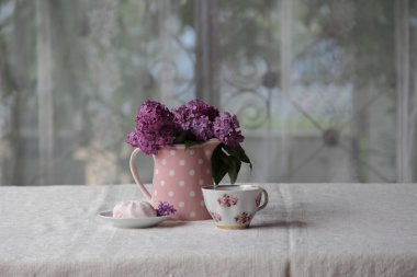 bir fincan çay ve şekerleme ve leylak sekmesinde bir buket