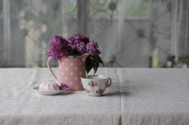 bir fincan çay ve şekerleme ve leylak sekmesinde bir buket