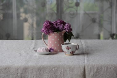 bir fincan çay ve şekerleme ve leylak sekmesinde bir buket