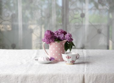 bir fincan çay ve şekerleme ve leylak sekmesinde bir buket