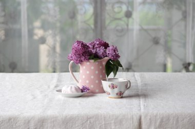 bir fincan çay ve şekerleme ve leylak sekmesinde bir buket