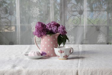 bir fincan çay ve şekerleme ve leylak sekmesinde bir buket