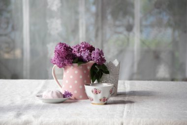 bir fincan çay ve şekerleme ve leylak sekmesinde bir buket