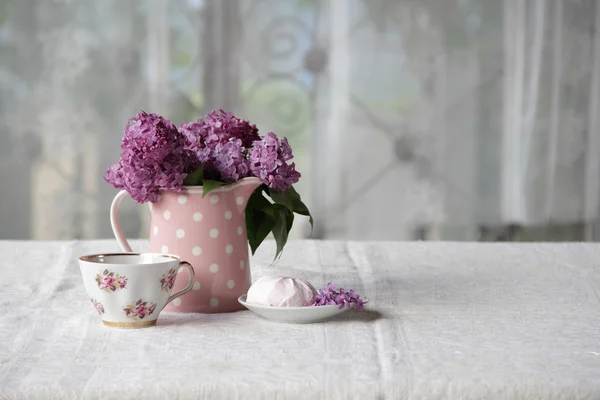 Uma xícara de chá e marshmallows e um buquê de lilases na aba — Fotografia de Stock