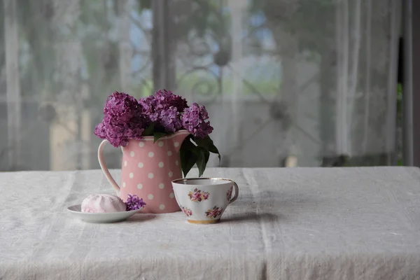 Eine Tasse Tee und Marshmallows und ein Strauß Flieder auf der Lasche — Stockfoto