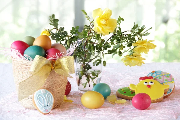 Bemalte Eier, Kekse und ein Strauß Rosen — Stockfoto