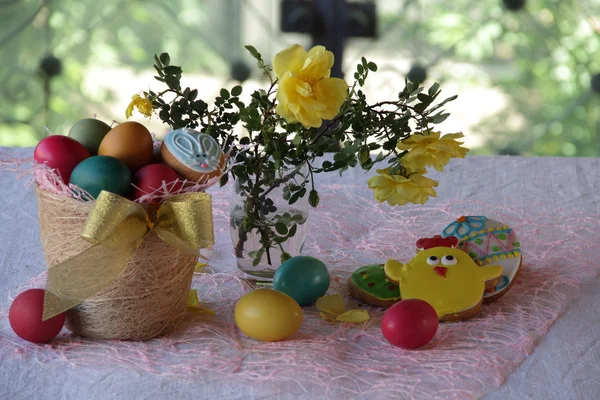 Bemalte Eier, Kekse und ein Strauß Rosen — Stockfoto