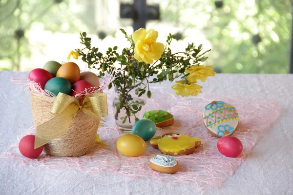 Ciasteczka maślane, malowane jajka w koszu i bukiet róż — Zdjęcie stockowe