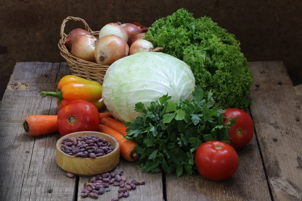 Feijão vermelho e verduras frescas em uma mesa de madeira — Fotografia de Stock