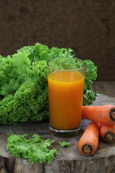 Морковный сок в прозрачном стакане и зеленый салат — стоковое фото