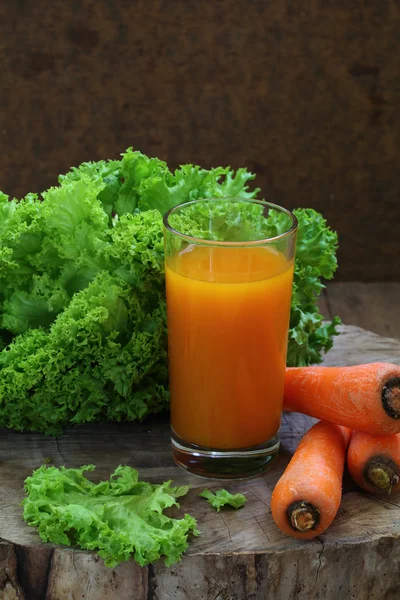 Морковный сок в прозрачном стакане и зеленый салат — стоковое фото